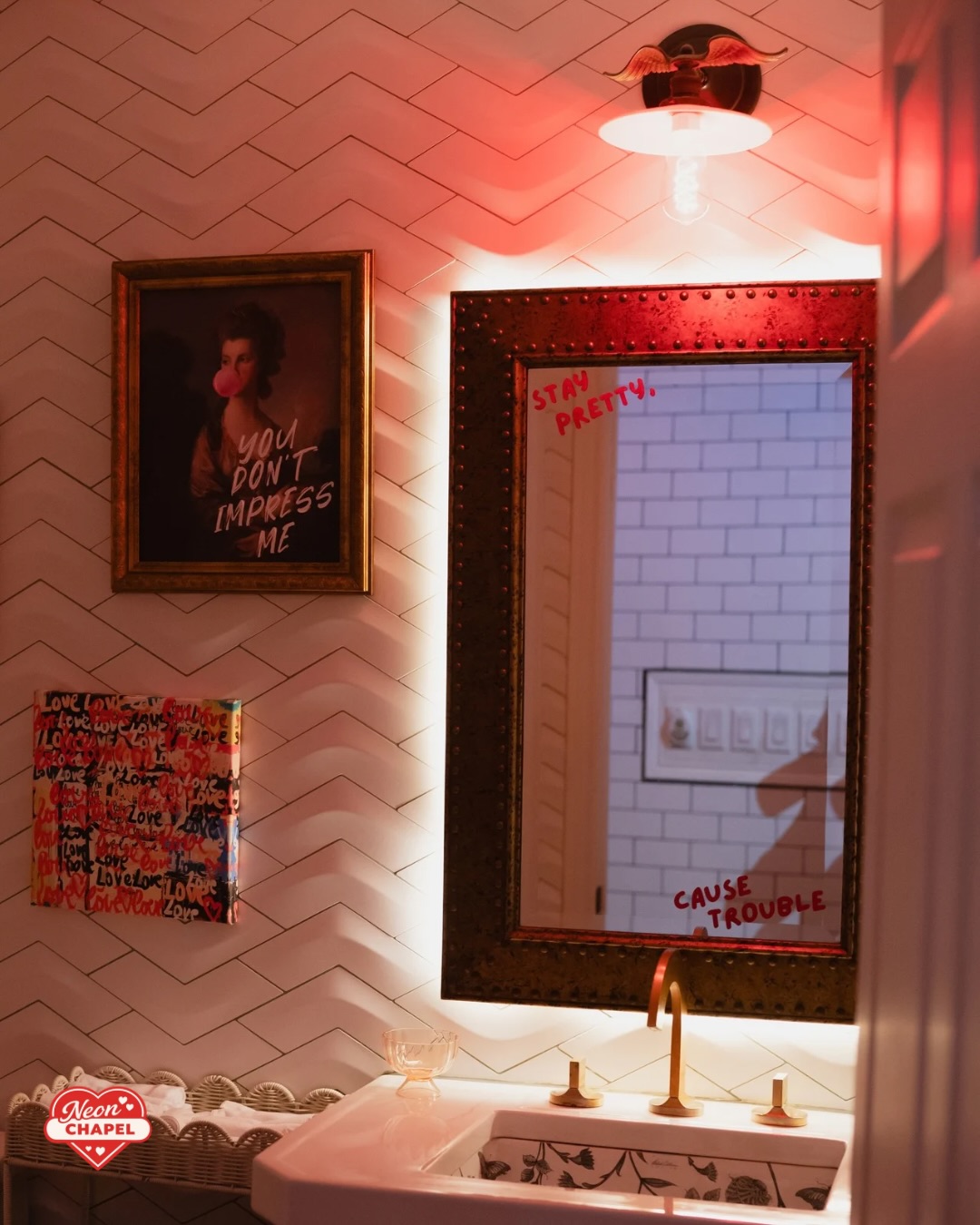Powder room with a backlit mirror reading Stay Pretty, Cause Trouble and a bubble-gum portrait print